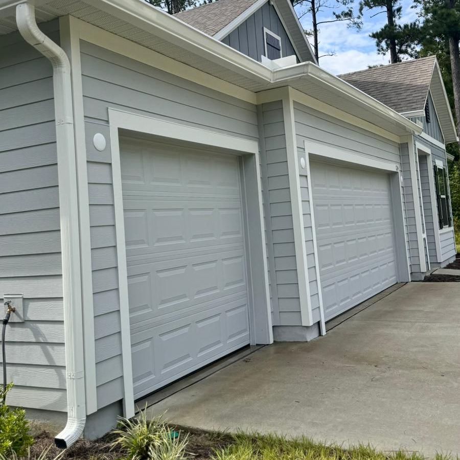 White gutters and a downspout on a gray two-car garage with white doors