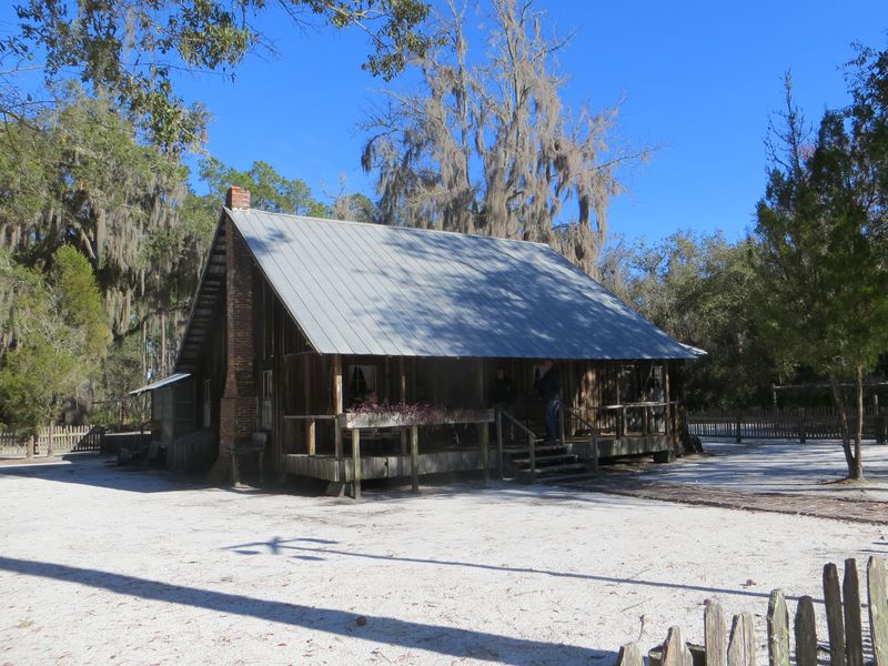 The Chesser Island Homestead in the Okefenokee refuge near Folkston, a board house with a metal roof and a swept white-sand yard under moss-hung trees