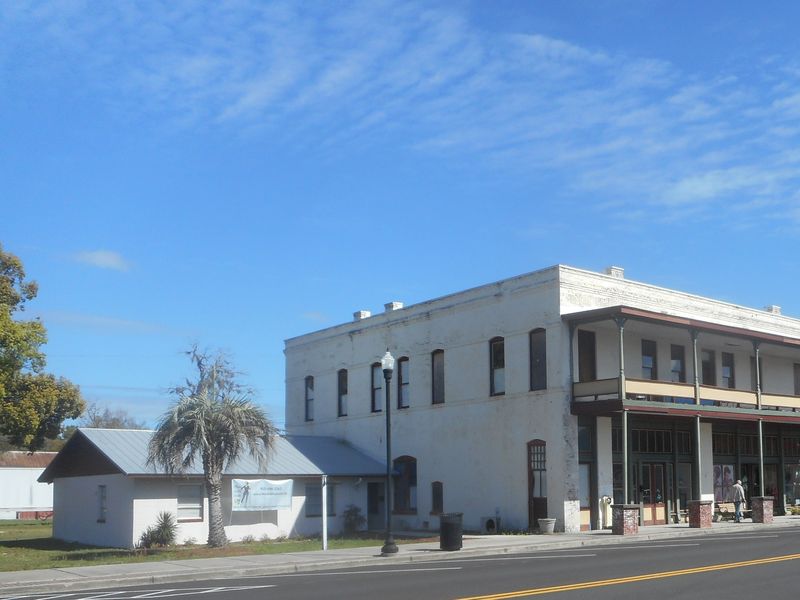 A two-story white-painted commercial building with a long upper balcony on West Main Street in Folkston, Georgia