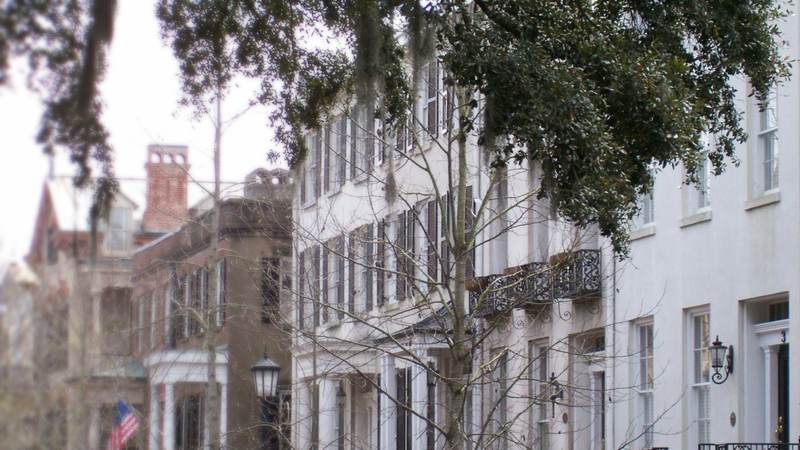 Historic townhouses with iron balconies behind oaks hung with Spanish moss on a Savannah street