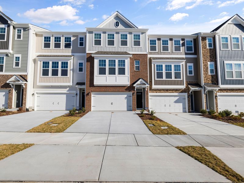 Row of new three-story townhomes with garages under one long shared roofline