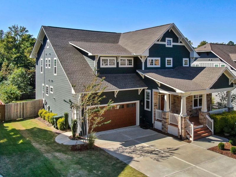 A two-story Craftsman-style house with dark siding, several gables, roof valleys and a lower porch roof