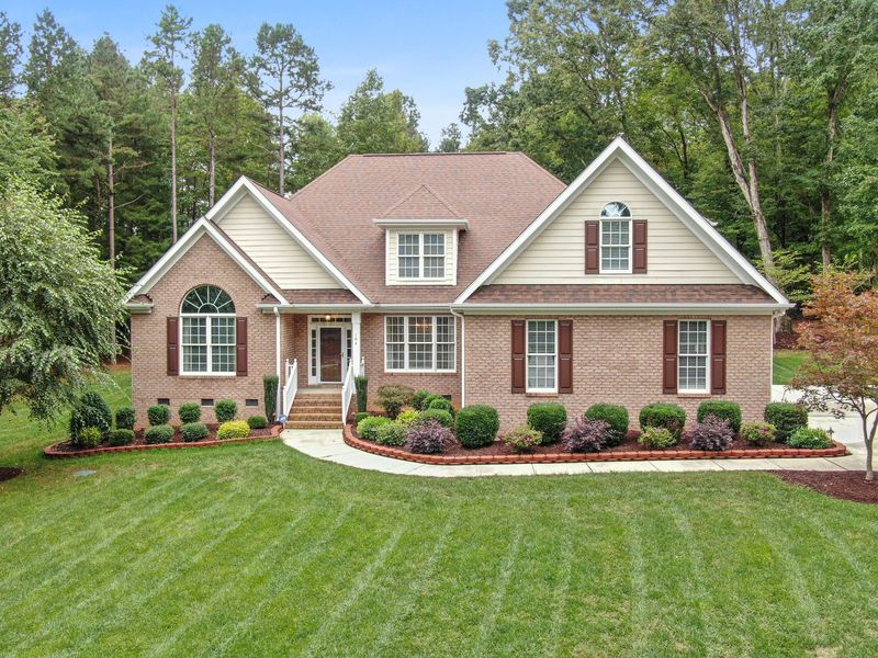 A brick-and-siding home with two front gables and a dormer, set against tall pines