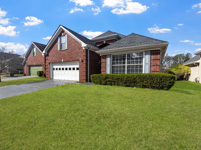 A red brick house with white gutters along the eaves and white downspouts at the corners