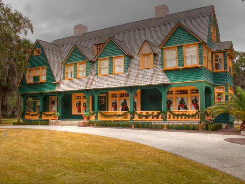 Moss Cottage, a green shingle-style house with a long front porch, in the Jekyll Island Club Historic District