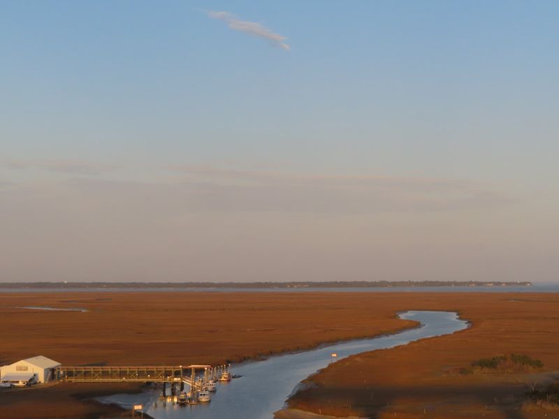A tidal creek winding through golden salt marsh to a boat dock near Brunswick, Georgia, at sunset
