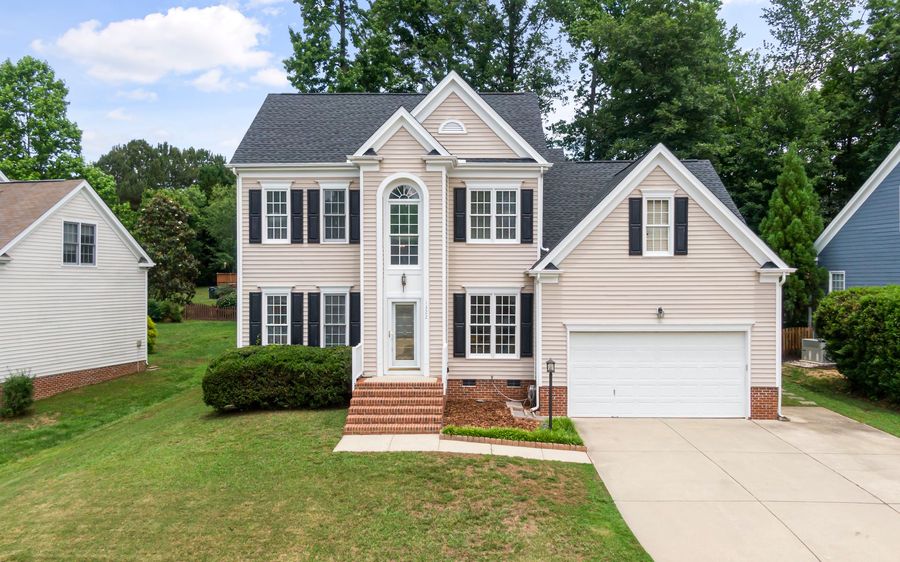 A two-story house with a brick front stoop, a two-car garage and a mowed front lawn