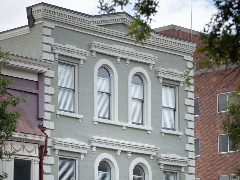 Historic two-story downtown commercial building with arched windows beside a storefront awning and downspout