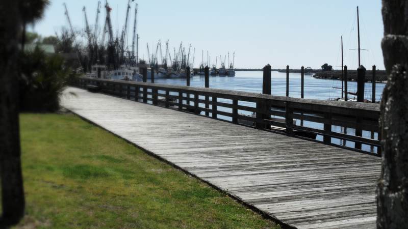 The boardwalk along the Darien waterfront, with shrimp boats tied up on the tidal river and salt marsh beyond