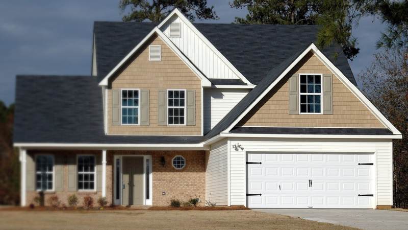A new two-story house with brick and tan siding, a double garage and long, straight eaves